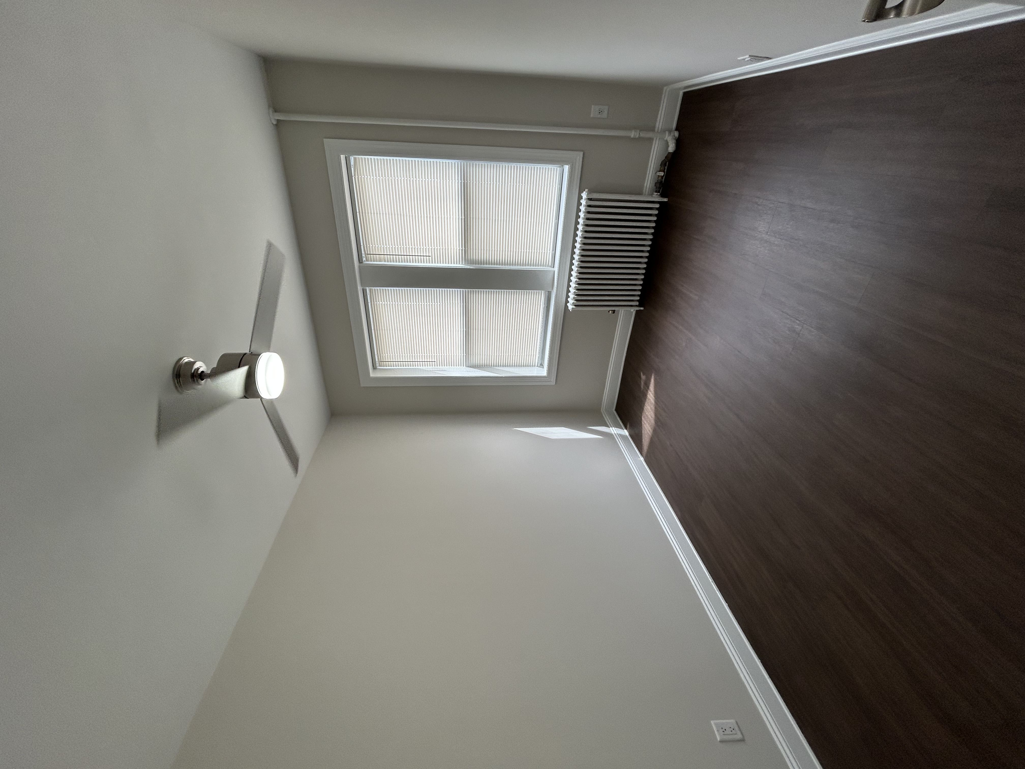 A room with a window and a light on the wall.